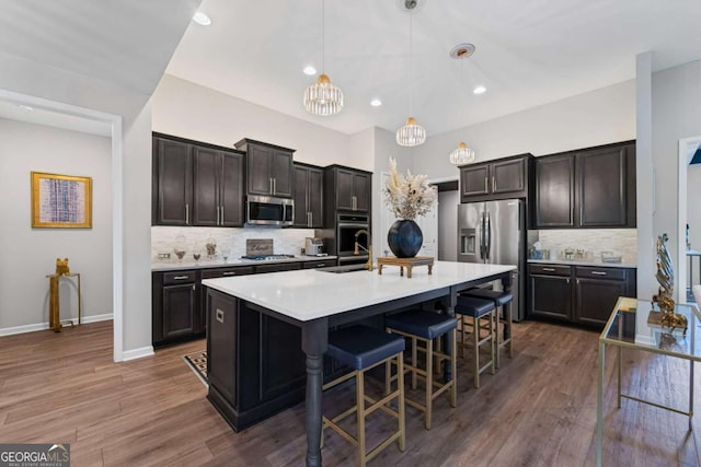 438 Southland Cir, Canton, GA 30115 - kitchen featuring stainless steel appliances, decorative backsplash, a breakfast bar area, light countertops, and dark wood-style flooring