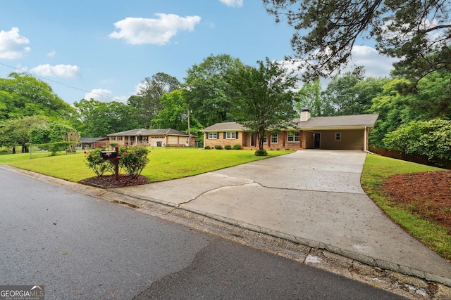 ranch-style home featuring driveway, a front yard, a chimney, a carport, and view of scattered trees