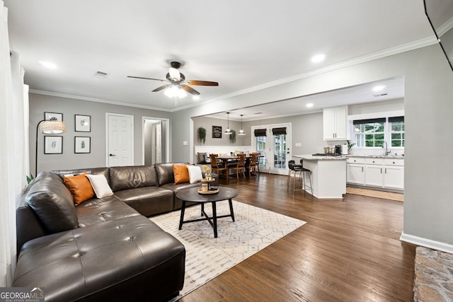 living room with a ceiling fan, dark wood finished floors, ornamental molding, and french doors