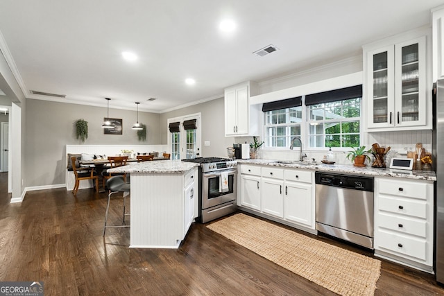 kitchen featuring appliances with stainless steel finishes, a sink, a peninsula, ornamental molding, and white cabinets