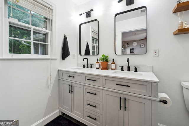 full bath with baseboards, toilet, and double vanity