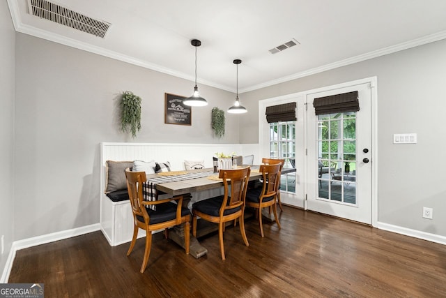 dining space featuring wood finished floors, ornamental molding, and baseboards