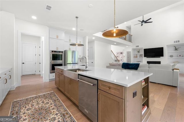 kitchen with appliances with stainless steel finishes, ceiling fan, a sink, light wood finished floors, and recessed lighting
