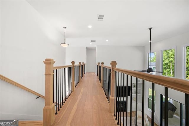 hallway with an upstairs landing, light wood-type flooring, baseboards, and recessed lighting