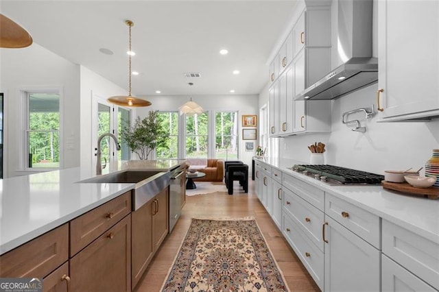 kitchen with wall chimney range hood, appliances with stainless steel finishes, light countertops, healthy amount of natural light, and recessed lighting
