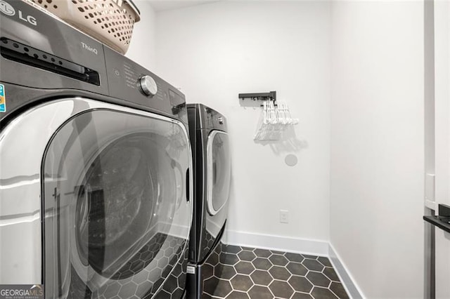 clothes washing area featuring independent washer and dryer, dark tile patterned flooring, and baseboards