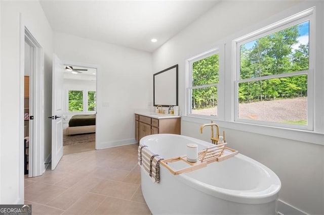 ensuite bathroom with vanity, a freestanding tub, baseboards, tile patterned floors, and recessed lighting