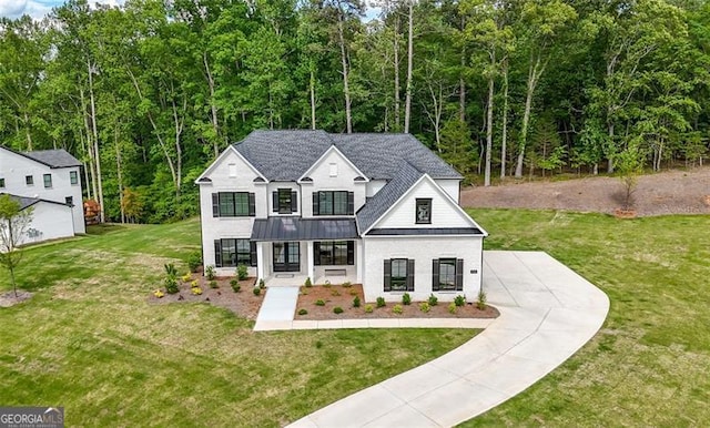 view of front facade featuring a standing seam roof, driveway, a front yard, covered porch, and a forest view
