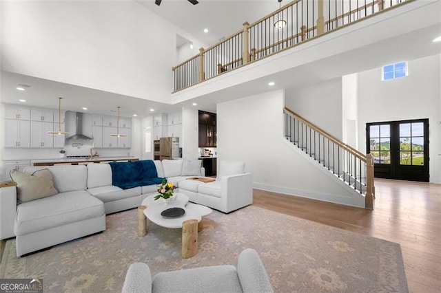 living area featuring a high ceiling, light wood-style flooring, stairs, ceiling fan, and recessed lighting