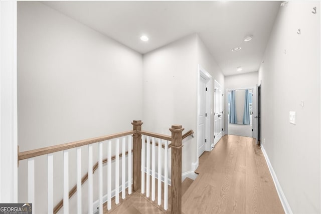hall with wood finished floors, an upstairs landing, recessed lighting, and baseboards