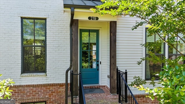 entrance to property featuring brick siding and a standing seam roof