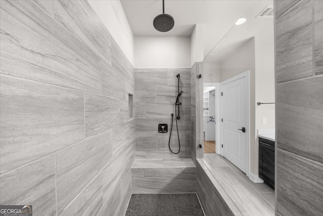 bathroom featuring a tile shower and vanity