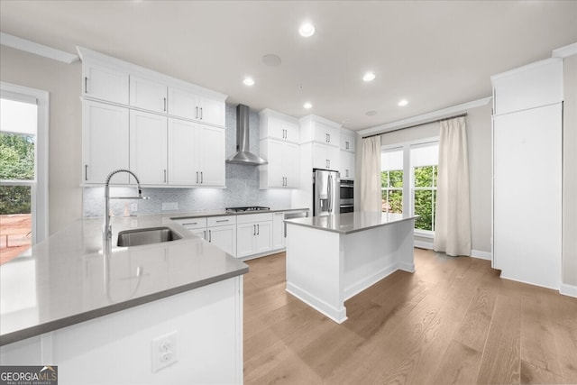 kitchen featuring a sink, wall chimney exhaust hood, stainless steel appliances, light wood-style flooring, and recessed lighting