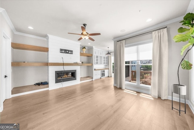 unfurnished living room with a fireplace, crown molding, wood finished floors, ceiling fan, and recessed lighting