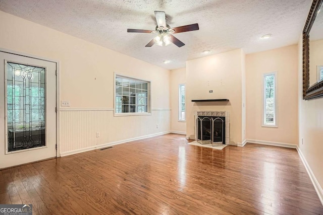 510 Aiken Dr, Dallas, GA 30157 - unfurnished living room with hardwood / wood-style flooring, a textured ceiling, a ceiling fan, a tile fireplace, and wainscoting