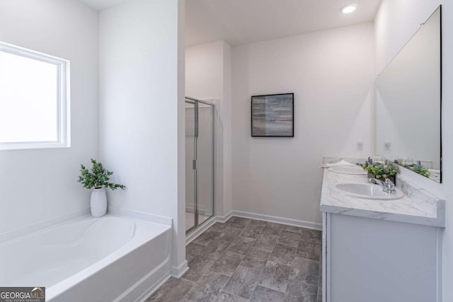 bathroom featuring a garden tub, a stall shower, double vanity, and baseboards