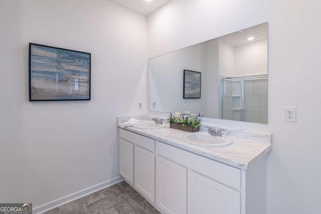 bathroom featuring baseboards, a stall shower, and double vanity