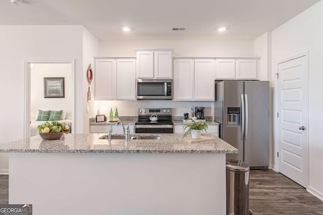 kitchen featuring stainless steel appliances, a sink, white cabinetry, an island with sink, and dark wood-style floors