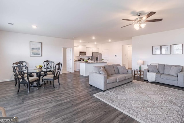 living room featuring dark wood-type flooring, a ceiling fan, baseboards, and recessed lighting