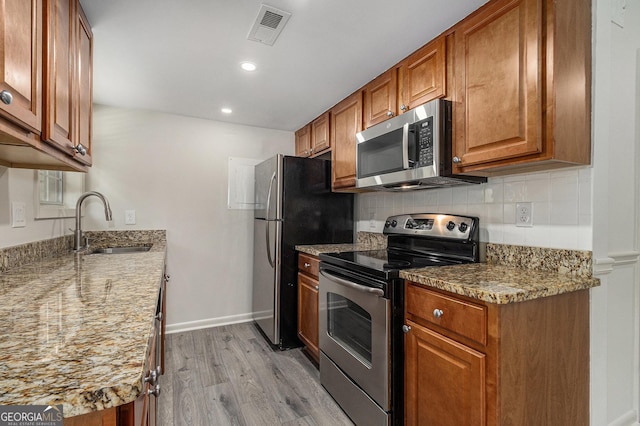6900 Roswell Rd Unit F6, Atlanta, GA 30328 - kitchen featuring stainless steel appliances, a sink, light wood-style floors, brown cabinets, and decorative backsplash