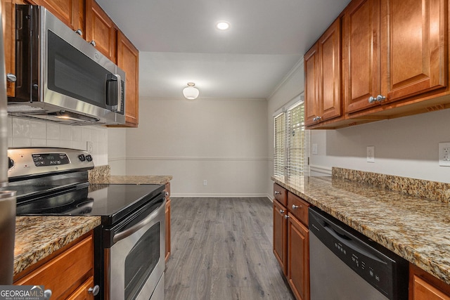 6900 Roswell Rd Unit F6, Atlanta, GA 30328 - kitchen with stainless steel appliances, brown cabinets, backsplash, wood finished floors, and ornamental molding