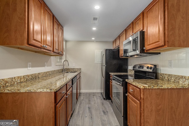 6900 Roswell Rd Unit F6, Atlanta, GA 30328 - kitchen featuring appliances with stainless steel finishes, light wood-style floors, brown cabinets, backsplash, and a sink