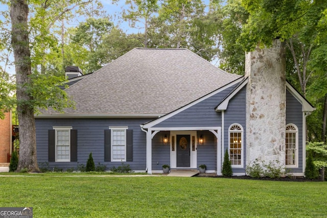 view of front facade with a chimney, a front lawn, and a shingled roof
