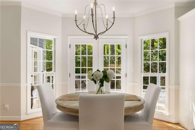 dining room with a chandelier, baseboards, light wood-type flooring, crown molding, and french doors