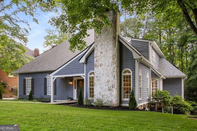 view of front of property featuring a chimney, a front lawn, and roof with shingles