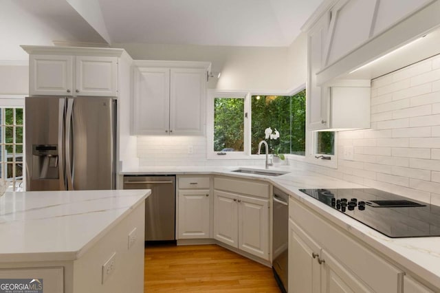 kitchen with appliances with stainless steel finishes, a sink, white cabinetry, and plenty of natural light