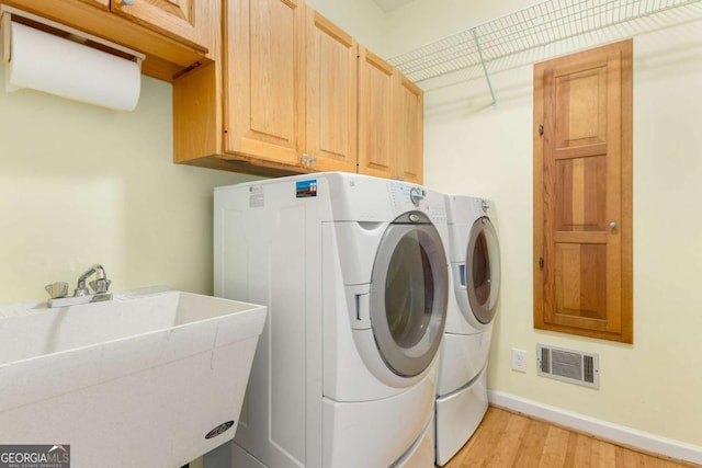 clothes washing area featuring cabinet space, independent washer and dryer, light wood-style floors, and baseboards
