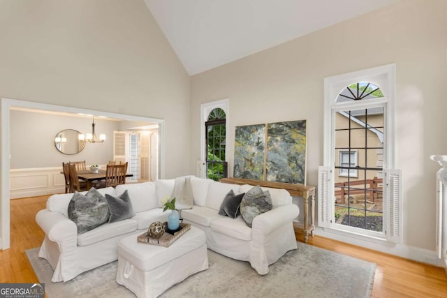 living room with a chandelier, high vaulted ceiling, and wood finished floors