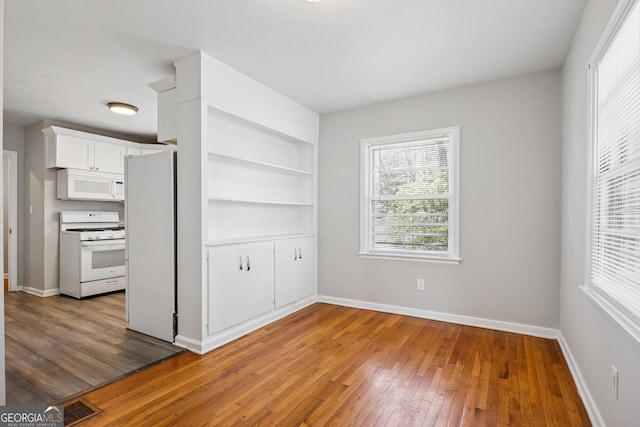 unfurnished dining area with hardwood / wood-style floors, baseboards, and built in shelves