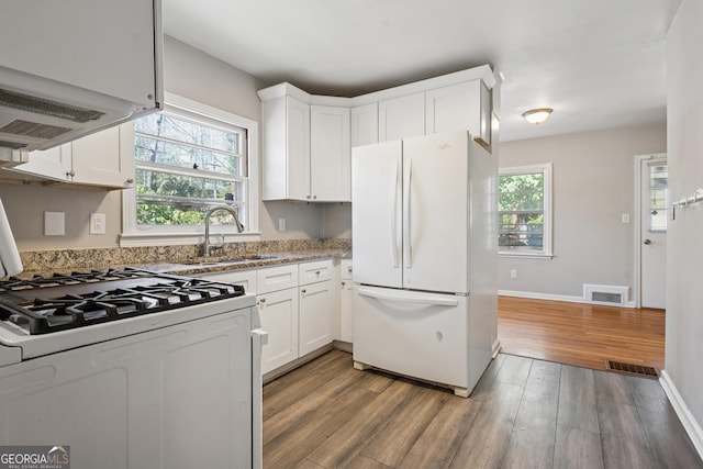kitchen with white appliances, a sink, light wood-type flooring, and white cabinetry