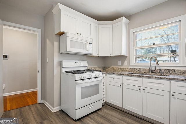 kitchen featuring white appliances, a sink, light stone counters, dark wood-type flooring, and white cabinetry