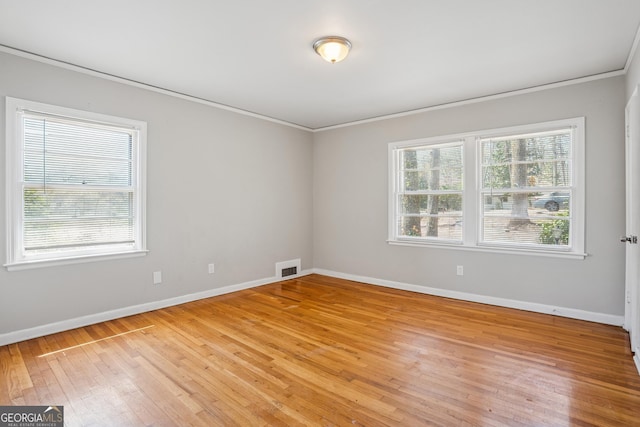 spare room featuring crown molding, light wood finished floors, and baseboards