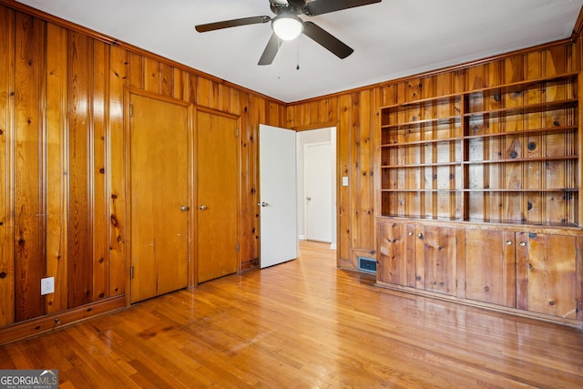 unfurnished bedroom featuring wood walls, wood finished floors, a closet, and crown molding