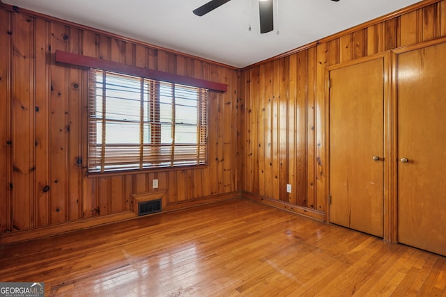unfurnished bedroom with wood-type flooring, wood walls, and baseboards