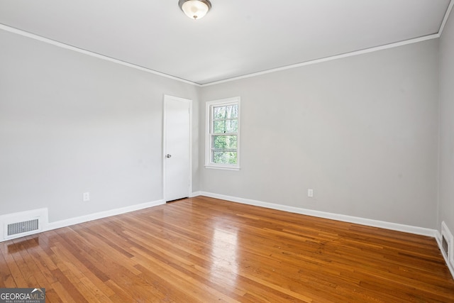 spare room featuring crown molding, light wood finished floors, and baseboards