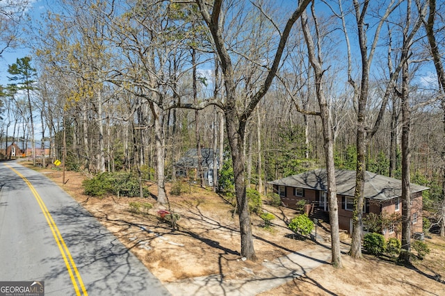 view of asphalt street featuring a forest view