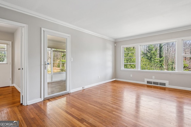empty room featuring light wood finished floors, baseboards, and ornamental molding