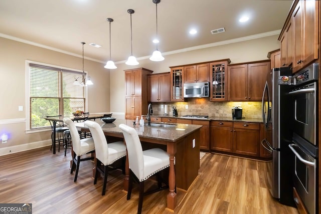 663 Warm Springs Ct, Loganville, GA 30052 - kitchen featuring stainless steel appliances, a kitchen bar, light wood-style flooring, brown cabinetry, and dark stone countertops