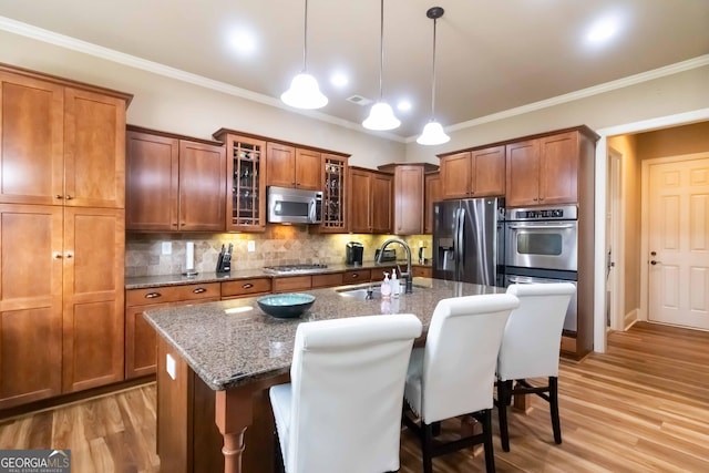 663 Warm Springs Ct, Loganville, GA 30052 - kitchen with appliances with stainless steel finishes, brown cabinetry, an island with sink, decorative backsplash, and crown molding