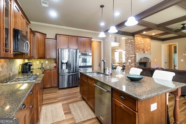 663 Warm Springs Ct, Loganville, GA 30052 - kitchen with appliances with stainless steel finishes, a kitchen bar, light wood-type flooring, brown cabinetry, and open floor plan