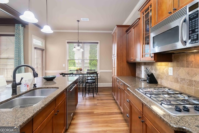 663 Warm Springs Ct, Loganville, GA 30052 - kitchen featuring stainless steel appliances, brown cabinets, light wood-style floors, and ornamental molding