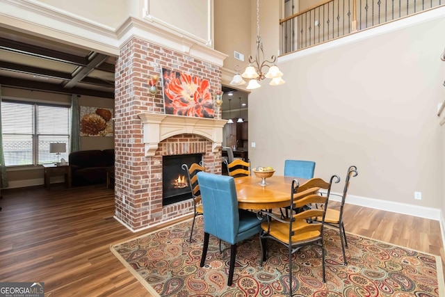 663 Warm Springs Ct, Loganville, GA 30052 - dining space with a fireplace, wood finished floors, coffered ceiling, beamed ceiling, and a chandelier