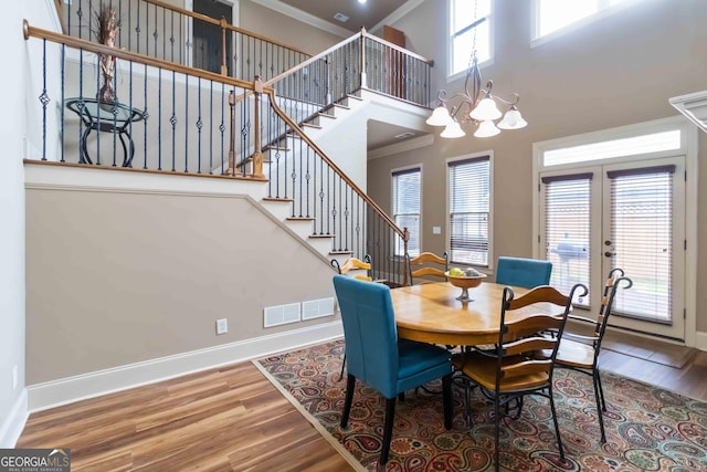663 Warm Springs Ct, Loganville, GA 30052 - dining room with wood finished floors, crown molding, stairway, a chandelier, and a high ceiling