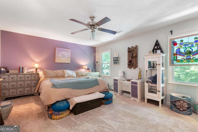 carpeted bedroom featuring multiple windows and a ceiling fan