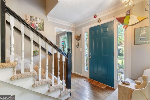 foyer featuring wood finished floors, crown molding, stairs, and baseboards