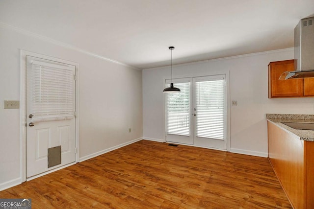 unfurnished dining area with crown molding, wood finished floors, and baseboards